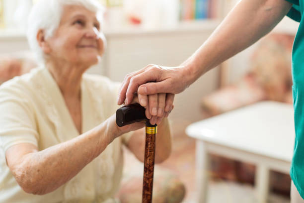 Aide soignante prenant la main d'une personne âgée